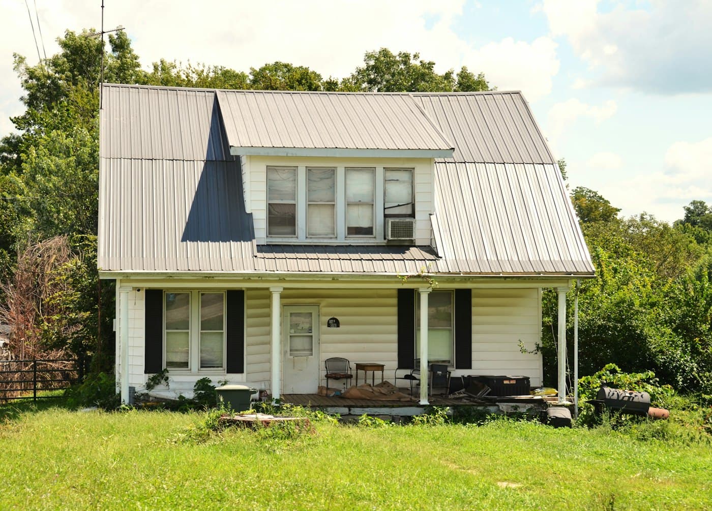 A two-story white frame house with a standing-seam metal roof and front porch